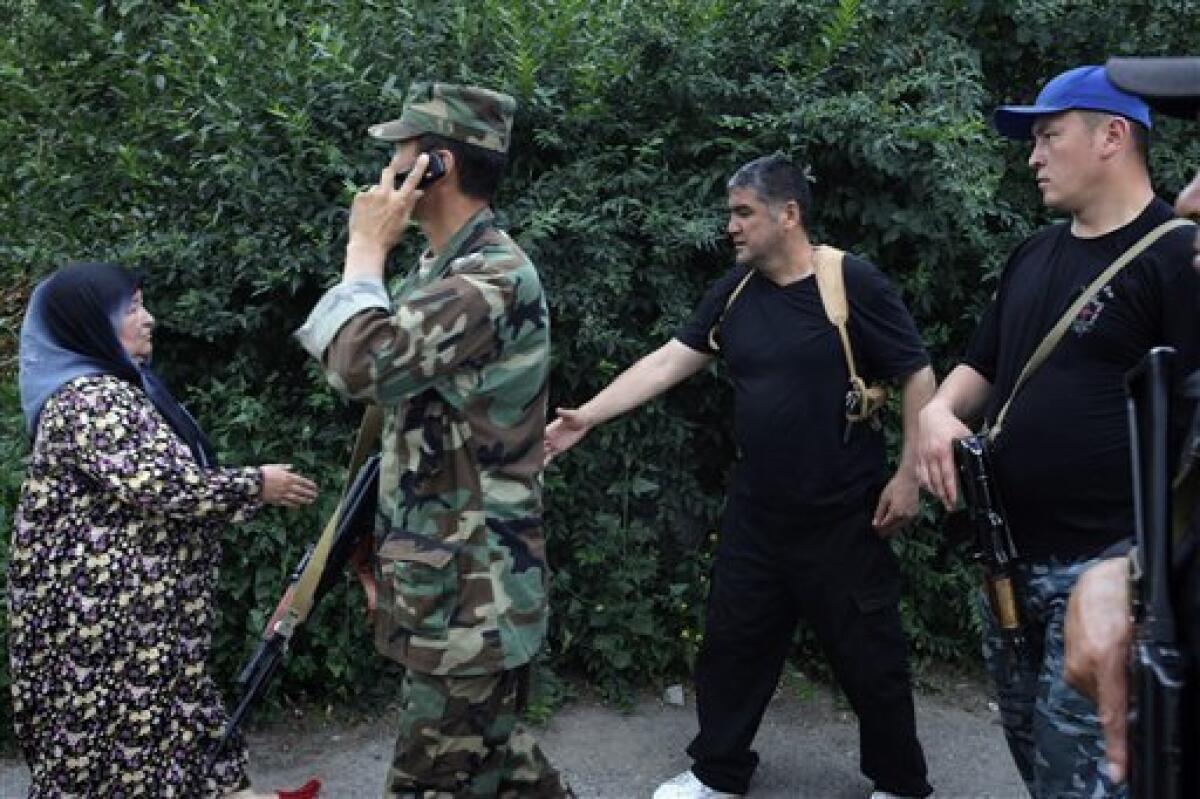 The head of local police, Colonel Kursan Asanov, second right, surround by special forces, greets an ethnic elderly Uzbek Kyrgyz citizen during peace negotiations, as he calls on ethnic Uzbeks to pull down a barricade between Uzbek and Kyrgyz districts in the southern Kyrgyz city of Osh, Kyrgyzstan, Friday, June 18, 2010. Kyrgyzstan's interim government leader Rosa Otunbayeva is vowing to work for the return of refugees who fled deadly ethnic violence there by the hundreds of thousands.(AP Photo/Alexander Zemlianichenko)