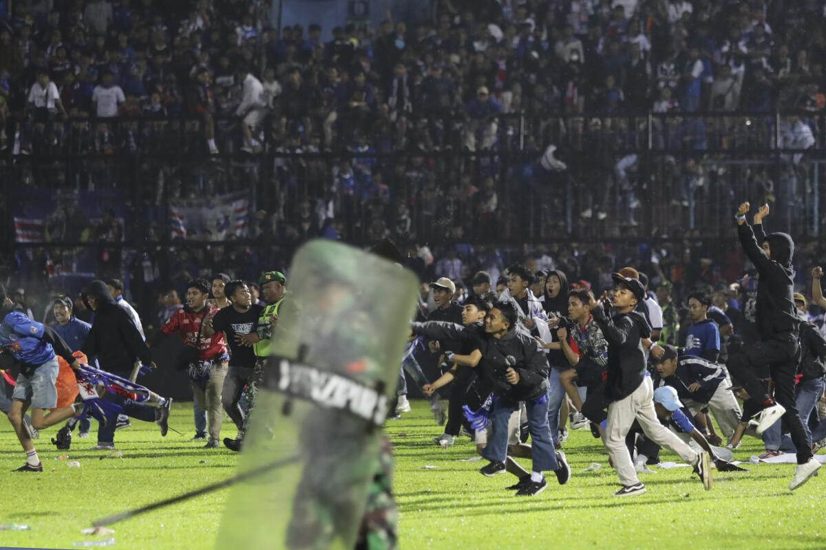 Soccer fans enter the pitch during a clash between supporters at Kanjuruhan Stadium in Malang, East Java, Indonesia, Saturday, Oct. 1, 2022. Clashes between supporters of two Indonesian soccer teams in East Java province killed over 100 fans and a number of police officers, mostly trampled to death, police said Sunday. (AP Photo/Yudha Prabowo)