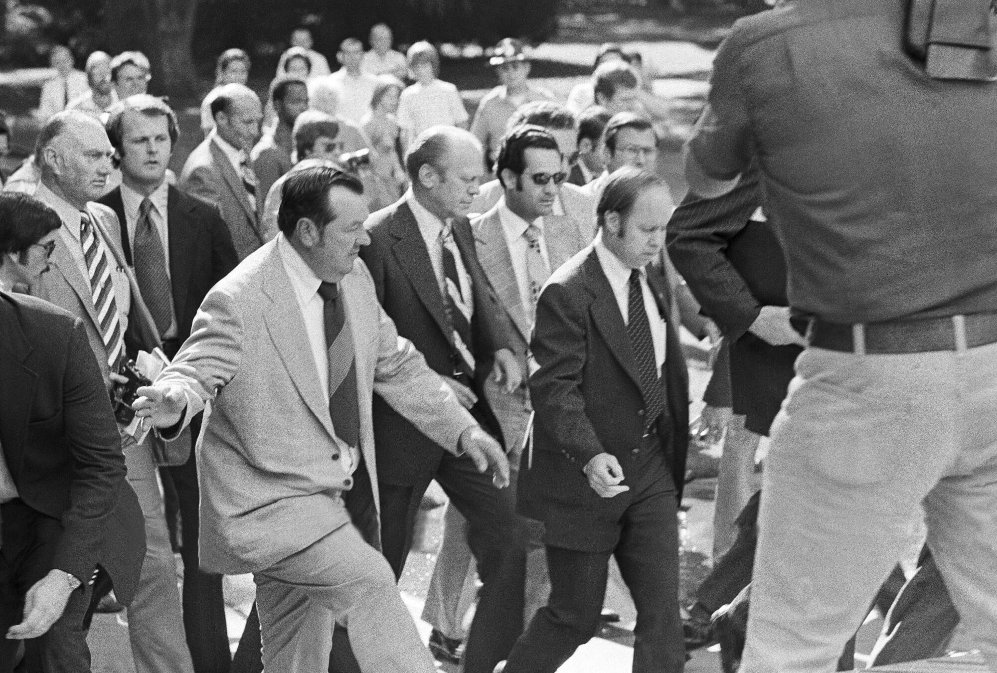 President Ford is hustled to safety by Secret Service agents.