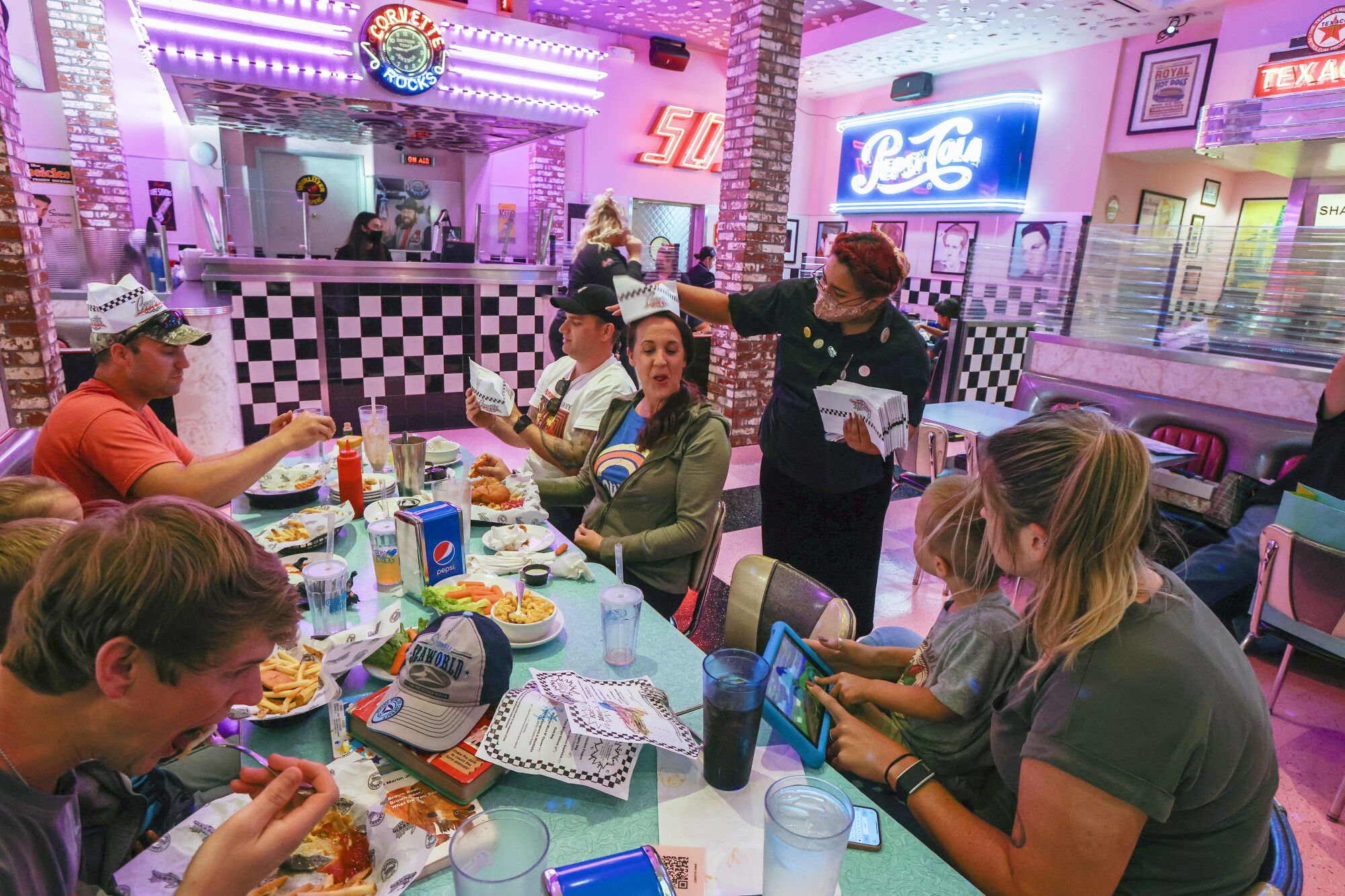 A server passes out hats last month at Corvette Diner in Liberty Station.