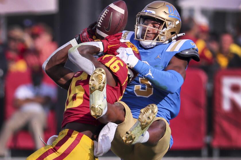 Los Angeles, CA - November 20: UCLA cornerback Cameron Johnson, right, bats a pass away from USC wide receiver Tahj Washington in the second quarter at Los Angeles Memorial Coliseum in Los Angeles on Saturday, Nov. 20, 2021. (Allen J. Schaben / Los Angeles Times)