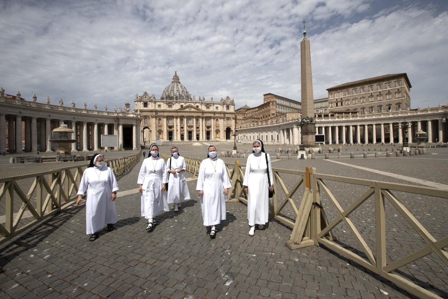 Nuns of St.Elisabeth wearing face masks to prevent the spread of COVID-19 leave St. Peter's Square after visiting St. Peter's Basilica at the Vatican in the day of its reopening, Monday, May 18, 2020. Italy is slowly lifting sanitary restrictions after a two-month coronavirus lockdown. (AP Photo/Alessandra Tarantino)