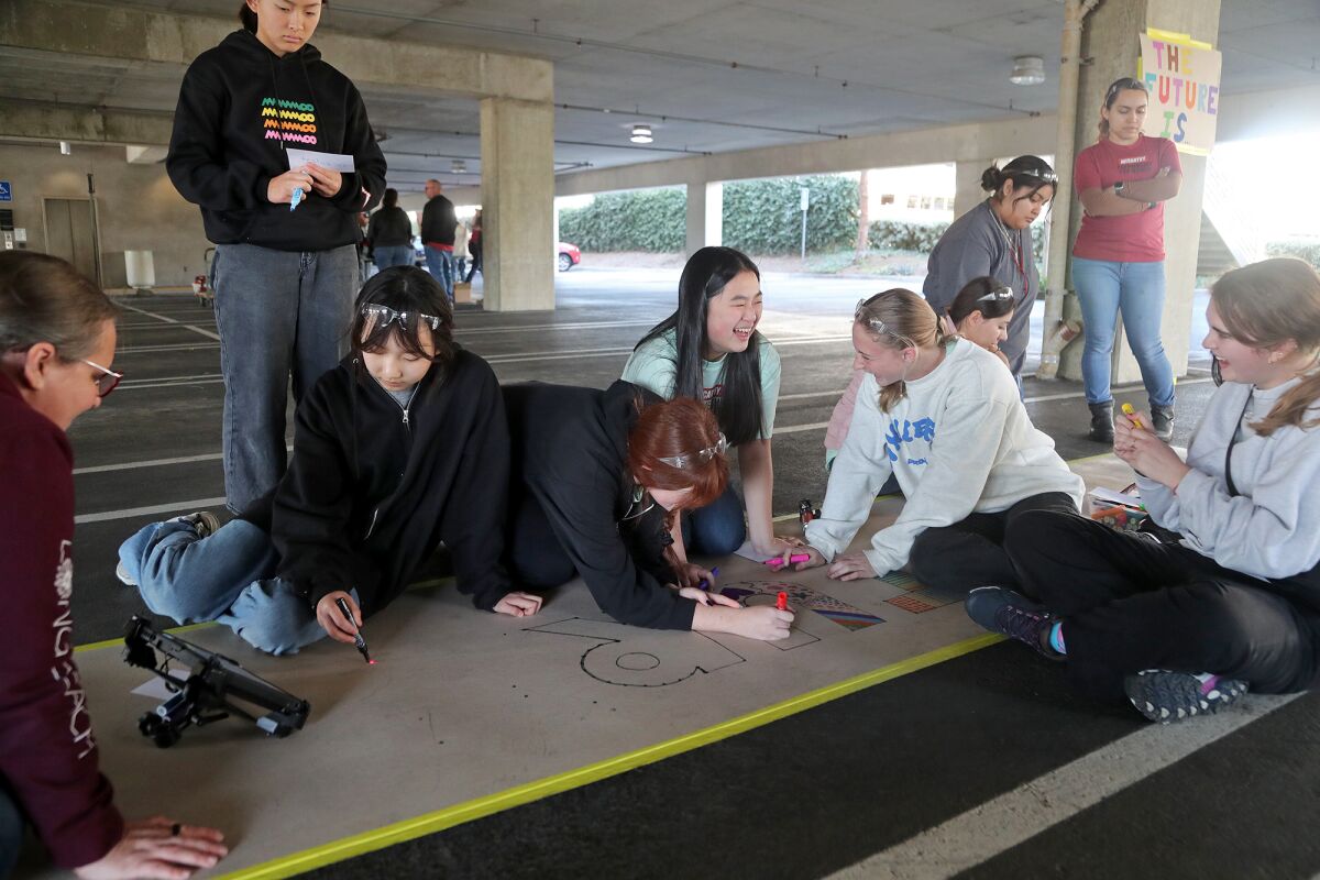 High School girls participate in a coloring activity at the Robotic Total Station area.