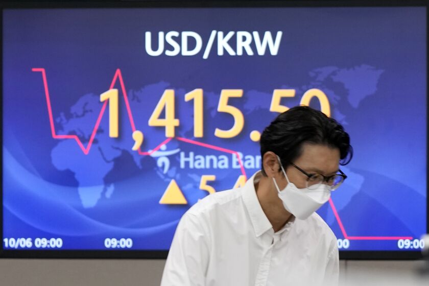 A currency trader walks by the screen showing the foreign exchange rate between U.S. dollar and South Korean won at a foreign exchange dealing room in Seoul, South Korea, Thursday, Oct. 6, 2022. Asian stocks were mixed Thursday after strong U.S. hiring dampened hopes the Federal Reserve might ease off plans for interest rate hikes and the OPEC group of oil exporters agreed to output cuts to shore up prices. (AP Photo/Lee Jin-man)