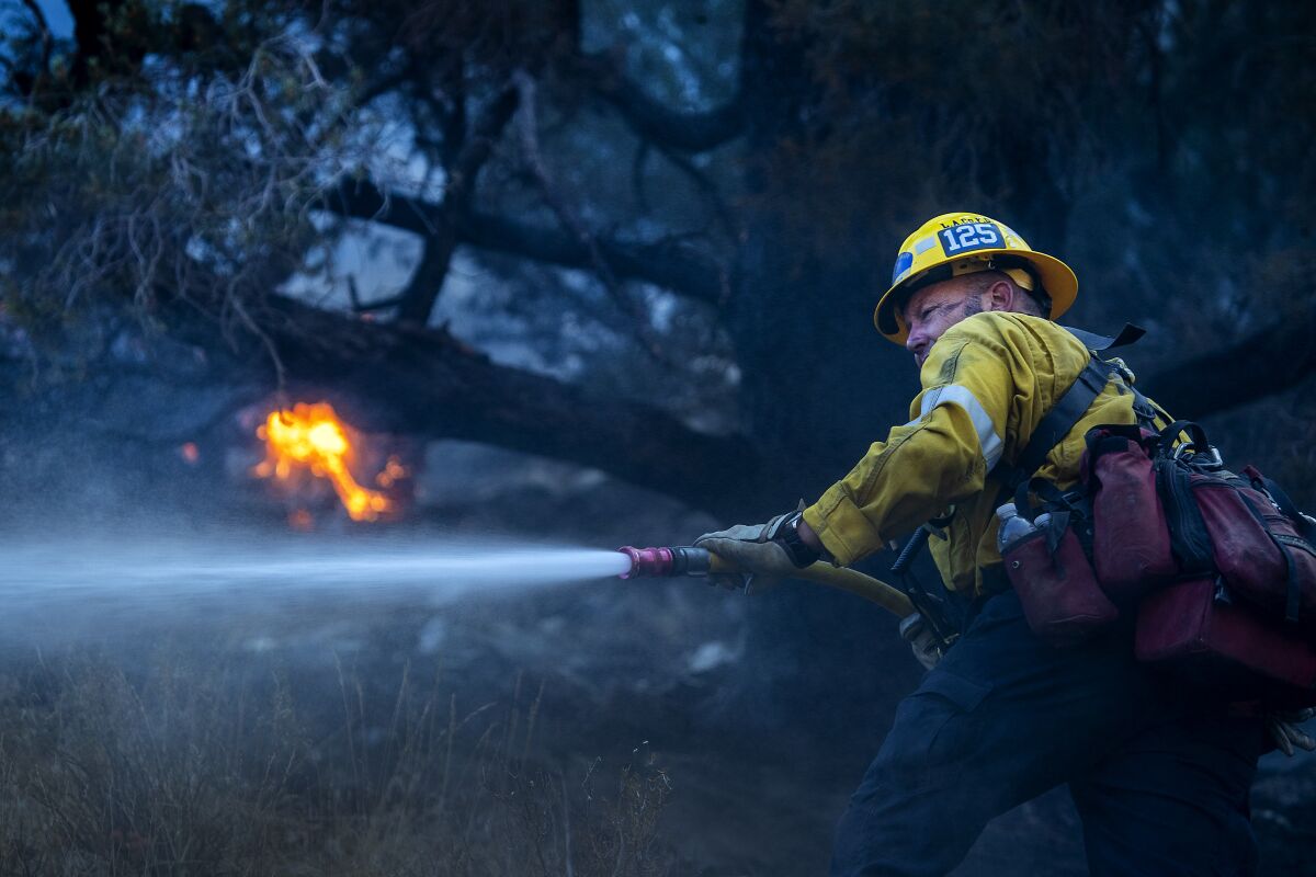 A firefighter blasts water out of a hose in the woods
