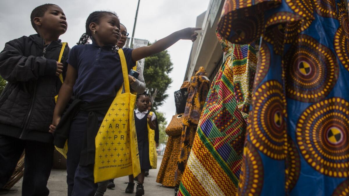 Schoolchildren view African dresses during a walk through Leimert Park.