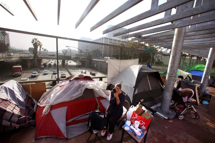 Alena, 45, cleans herself along Main Street where she lives in a tent with many other homeless above the 101 Freeway in downtown Los Angeles. "I'm new to this unexpected homelessness," she said. She was laid off from her job as an administrative assistant this year.
