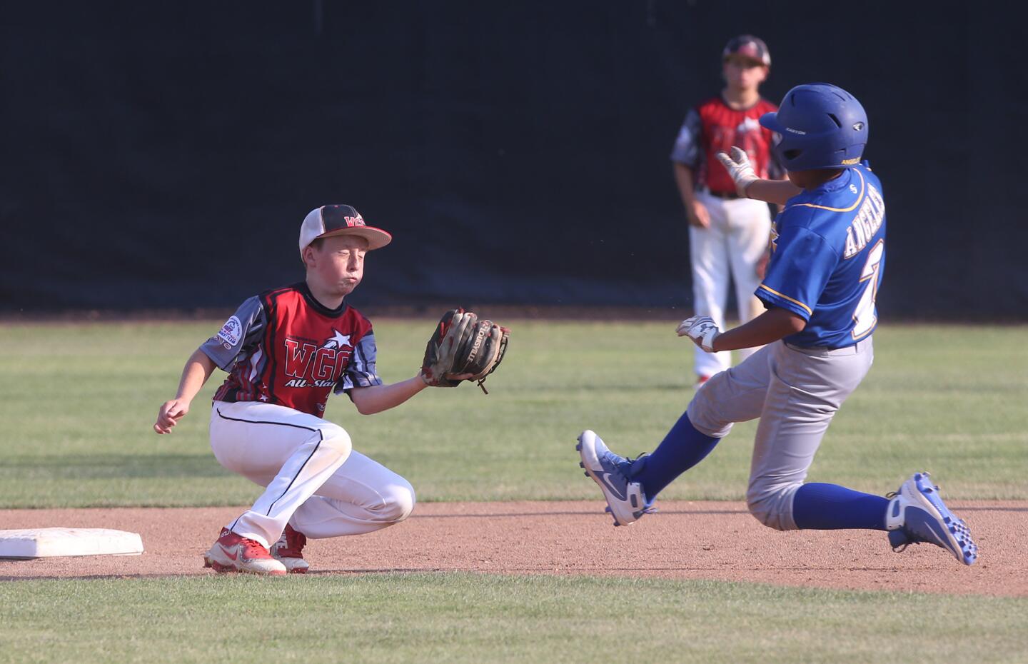 Fountain Valley's Eric Angeles slides into second as West Garden Grove short Troy Atkins prepares to tag in the PONY Bronco 12-and-under Section tournament at Del Obispo Community Park in Dana Point on Friday.