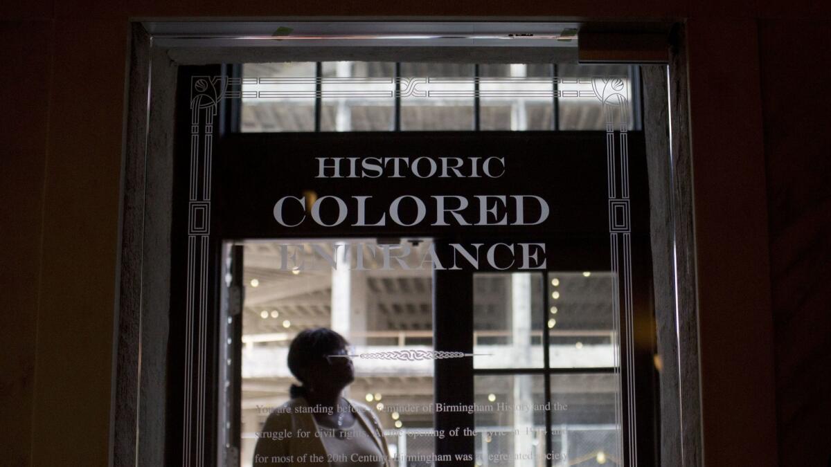 In this Jan. 7, 2016 photo, a woman stands in the doorway of then new Historic Colored Entrance at the Lyric Theatre, in Birmingham, Ala.