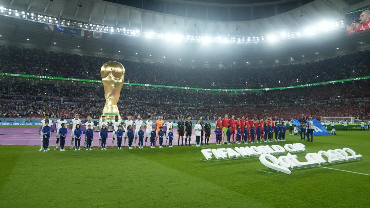 Players on the United States and Wales line up on the field before their World Cup match Monday.