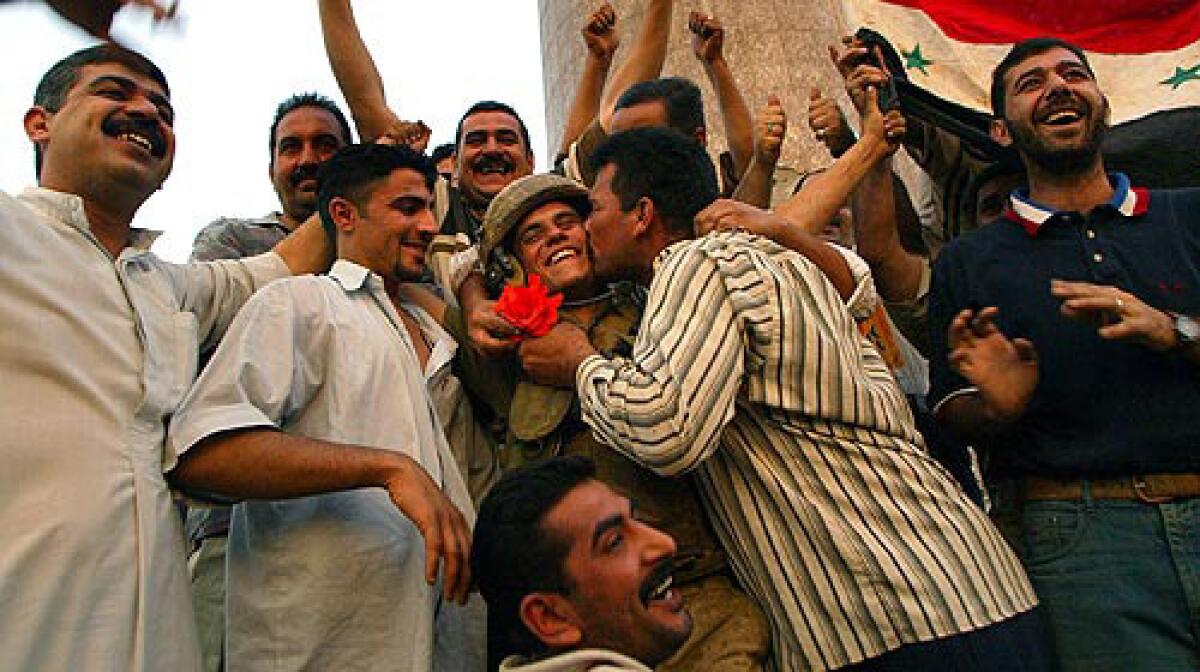 Marine Lance Cpl. Shawn Hicks gets a kiss from a man in Baghdad's Firdos Square on April 9, 2003, as Iraqis celebrate the arrival of U.S. troops in the city and the end of Saddam Hussein's regime.