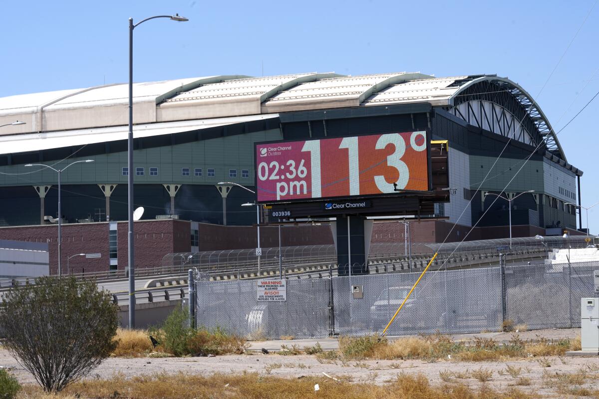 A digital billboard outside a large building shows a temperature of 113 degrees.