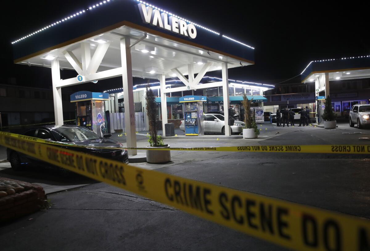 Police tape is seen in the foreground with a Valero gas station in the back.
