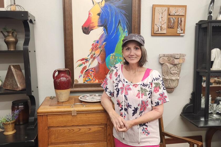 Diana Taylor, owner of Vintage Vibes, in front of one of her favorite art pieces