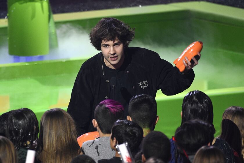 David Dobrik in a crowd holding an orange Nickelodeon blimp trophy