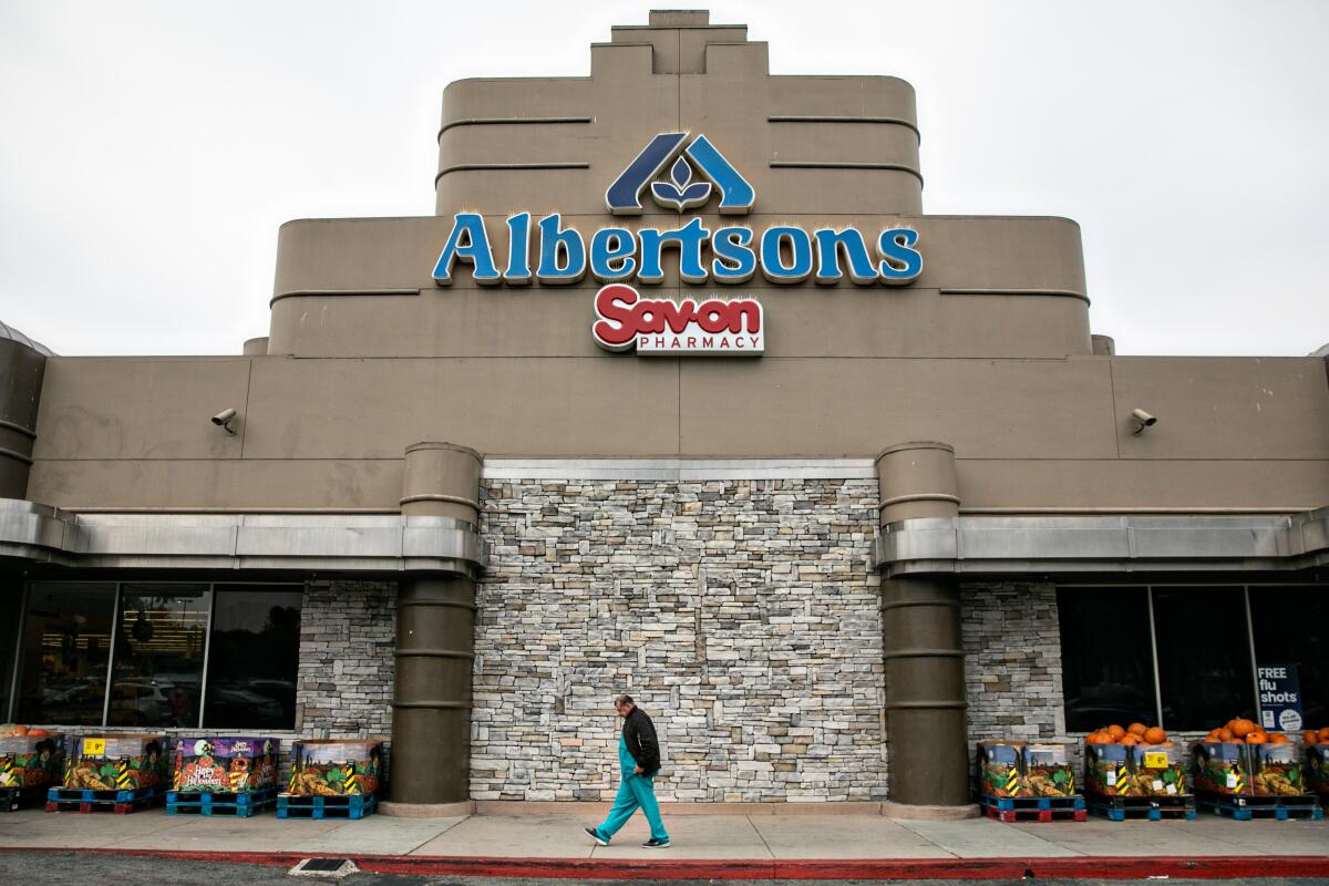 A person walks in front of an Albertsons store.