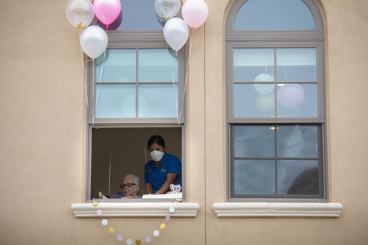 A resident and staff member seen through a second-story window at an assisted living facility in Redondo Beach. 