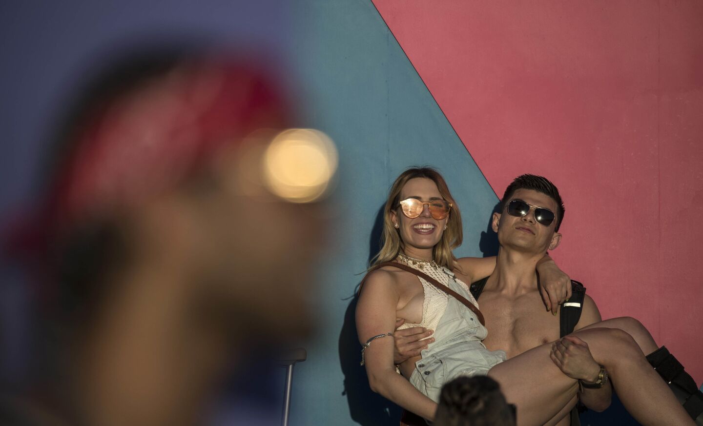 INDIO, CALIF. -- FRIDAY, APRIL 14, 2017: Coachell goers pose for photos against 'this is what brings things into focus?' installation as the sun goes down on day one at the Coachella Music and Arts Festival in Indio, Calif., on April 14, 2017. (Brian van der Brug / Los Angeles Times)