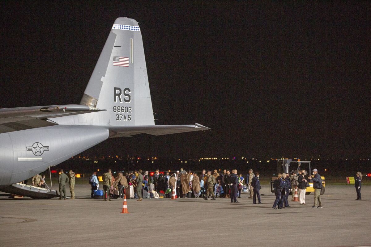 In this Aug. 29, 2021, file photo families evacuated from Kabul, Afghanistan, walk past a U.S Air Force plane.