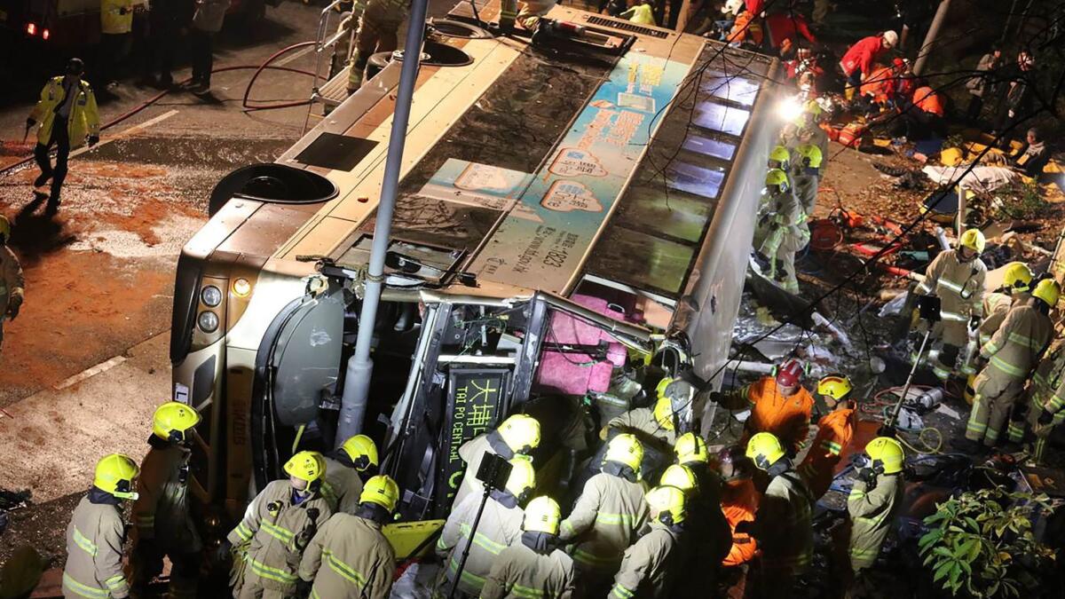 Crews work at the scene after a bus toppled near the town of Tai Po in Hong Kong's northern New Territories.