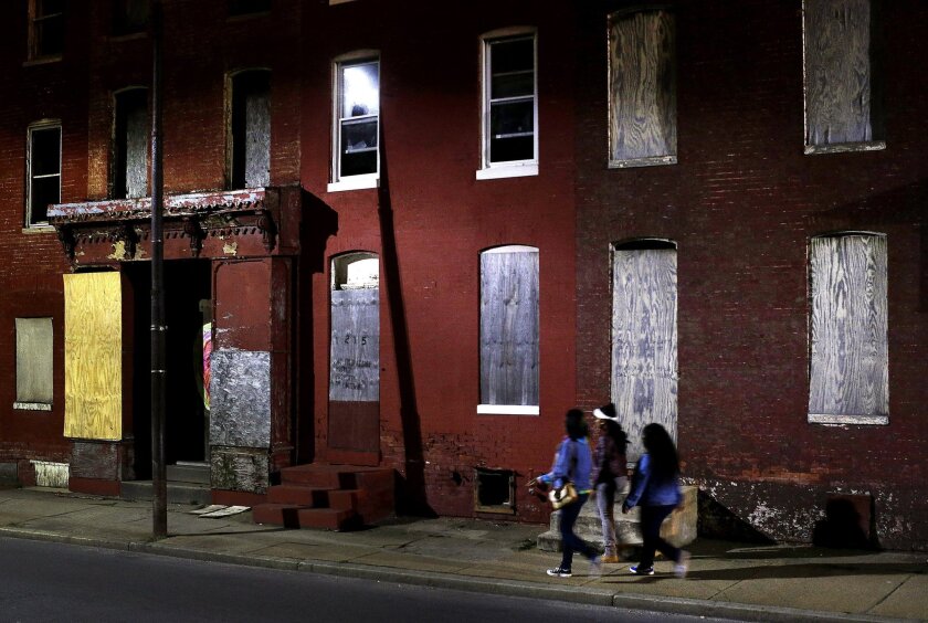 Women walk past blighted row houses in Baltimore in 2013.