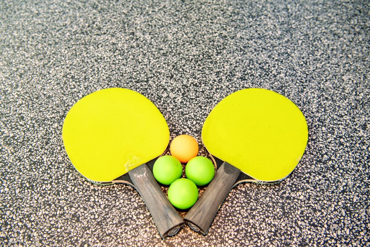 Duas raquetes de pingue-pongue com quatro bolas entre elas