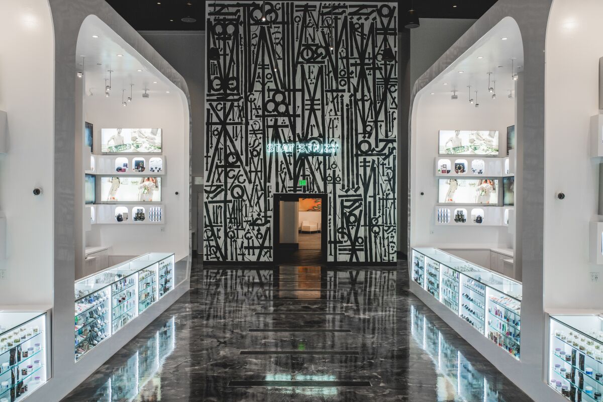 A dispensary interior with brightly lit cabinets and an art-filled wall.