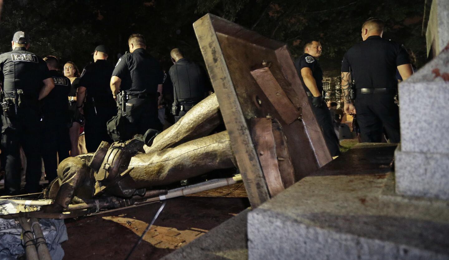 Police stand guard after a Confederate statue was toppled by protesters on campus at the University of North Carolina on Aug. 20, 2018.