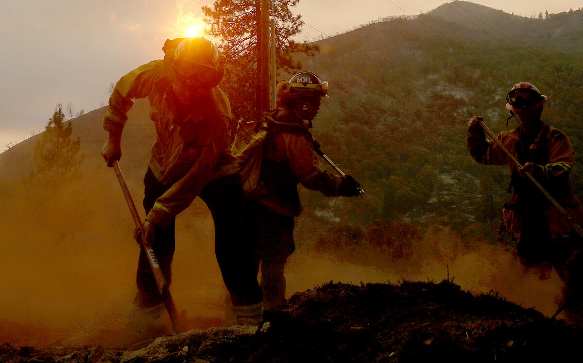 Firefighters put out hot spots from the Oak fire along Darrah Road near Mariposa on Tuesday.