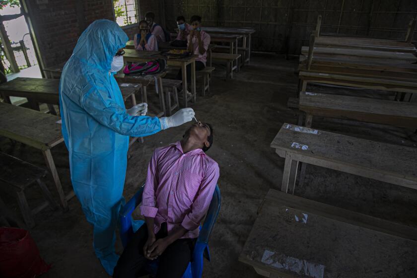 An Indian health worker takes a nasal swab sample of a student to test for coronavirus after classes started at a college in Jhargaon village, outskirts of Gauhati, India, Wednesday, Sept. 30, 2020. India's Health Ministry on Wednesday raised its confirmed total of coronavirus cases to more than 6.2 million. (AP Photo/Anupam Nath)