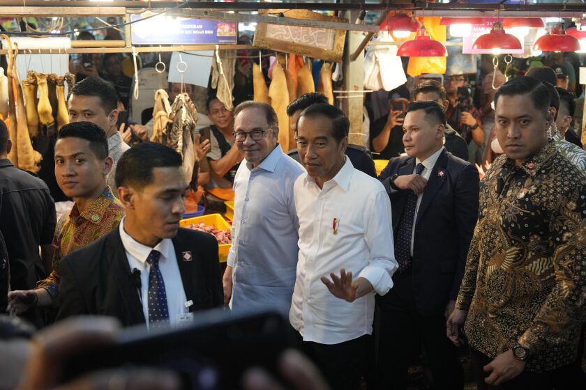 Indonesian President Joko Widodo, center, walks with Malaysian Prime Minister Anwar Ibrahim as they visit a local wet market in Kuala Lumpur, Malaysia, Thursday, June 8, 2023. (AP Photo/Vincent Thian)