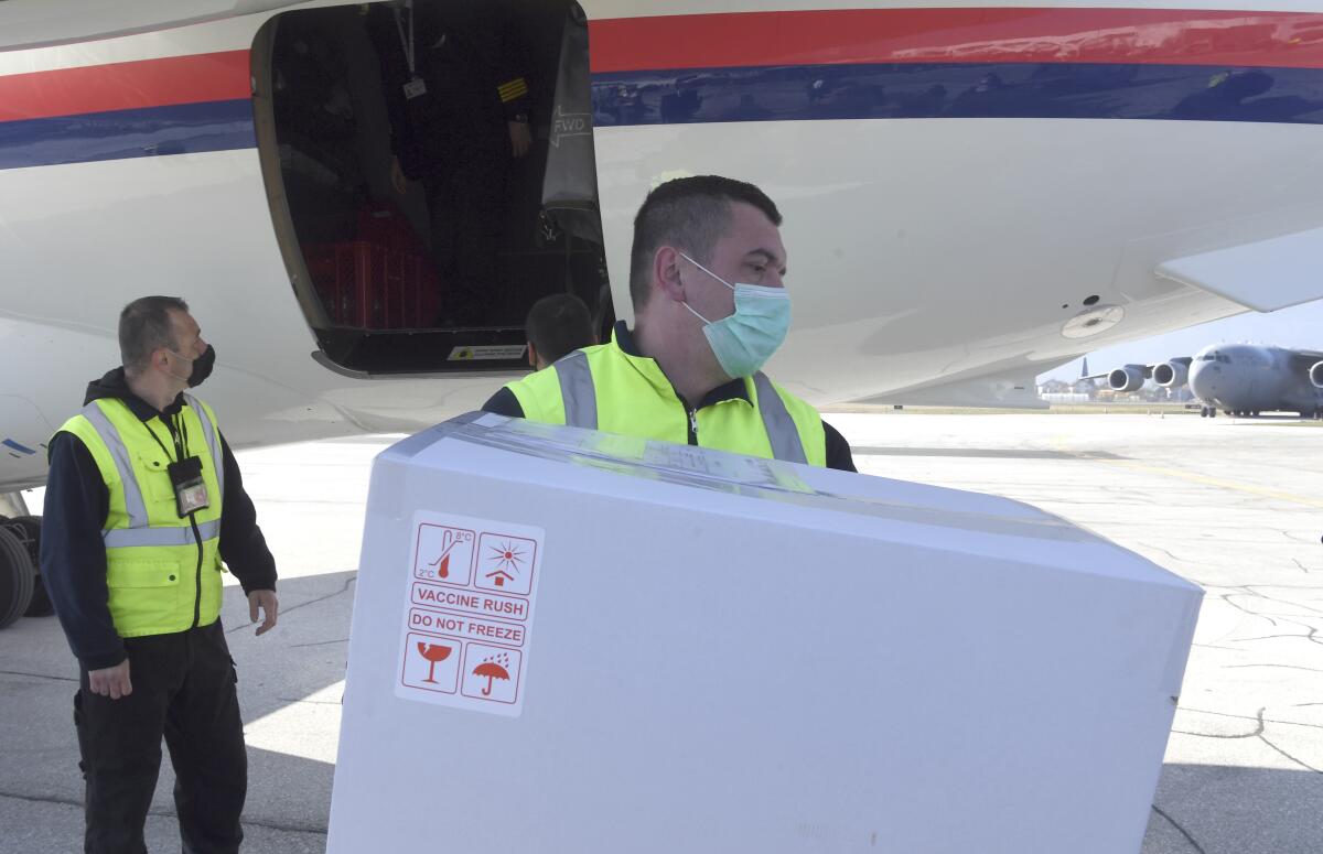 In this photo provided by the Serbian Presidential Press Service, a worker holds a box of the Astra-Zeneca vaccines at Sarajevo Airport, Bosnia, Tuesday, March 2. 2021. Bosnia on Tuesday received 10,000 vaccines from neighboring Serbia amid a dispute with the international COVAX mechanism over a delay in planned shipments. Serbia's populist President Aleksandar Vucic flew to the Bosnian capital of Sarajevo to deliver the Astra-Zeneca vaccines to the authorities there. (Serbian Presidential Press Service via AP)