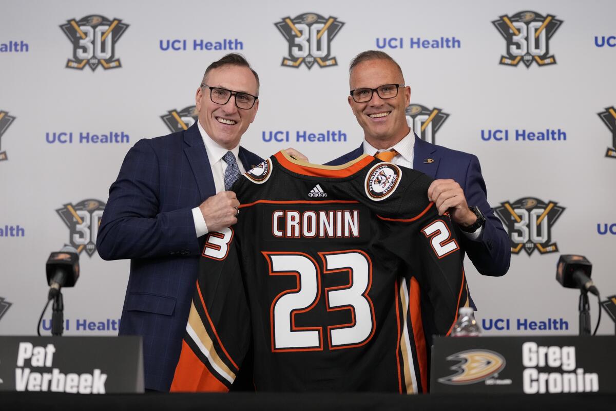 Ducks General Manager Pat Verbeek holds a Ducks jersey with new head coach Greg Cronin.