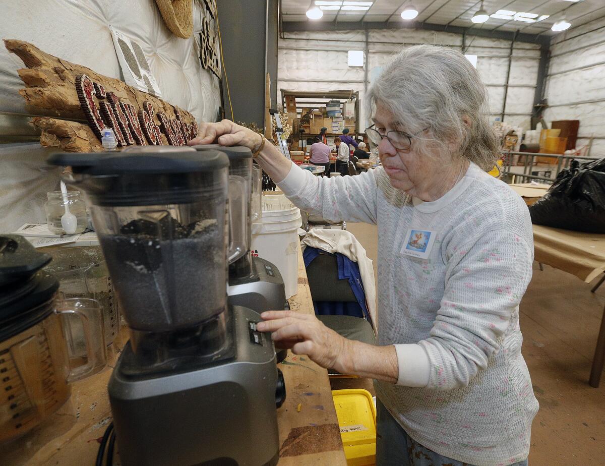 Longtime volunteer Debbie Curtin, with the Burbank Tournament of Roses Assn., mixes rice and onion seeds in a blender to match a lighter color of gray for the organization's float entry, called "Rise Up," on Friday.