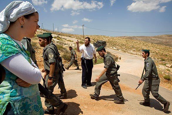 Jewish settlers watch Israeli border police after they demolished seven structures in the outpost of Maoz Esther, a hilltop site northeast of Ramallah, in the West Bank. The forces moved against the outpost, comprising about 40 people living in seven metal huts, three days after President Barack Obama told visiting Prime Minister Benjamin Netanyahu that he must halt settlement activity.