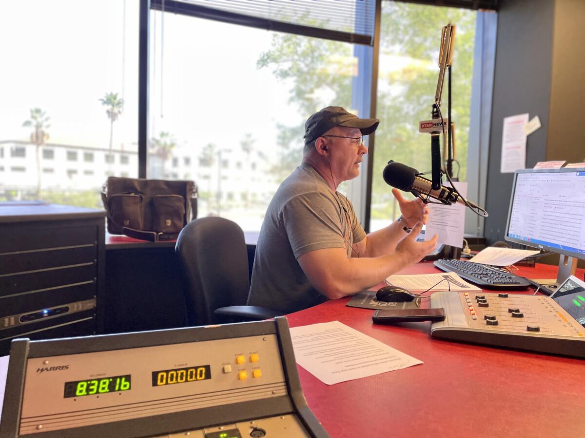 Mike Broomhead, in glasses and T-shirt, sits at his radio booth.