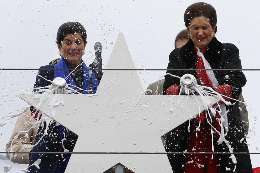 Luci Baines Johnson, left, and her sister, Lynda Johnson Robb, smash champagne bottles to christen the Lyndon B. Johnson, the third Zumwalt-class guided missile destroyer, built at Bath Iron Works, Saturday, April 27, 2019, in Bath, Maine. Johnson and Robb and the daughters of the former president. (AP Photo/Robert F. Bukaty)