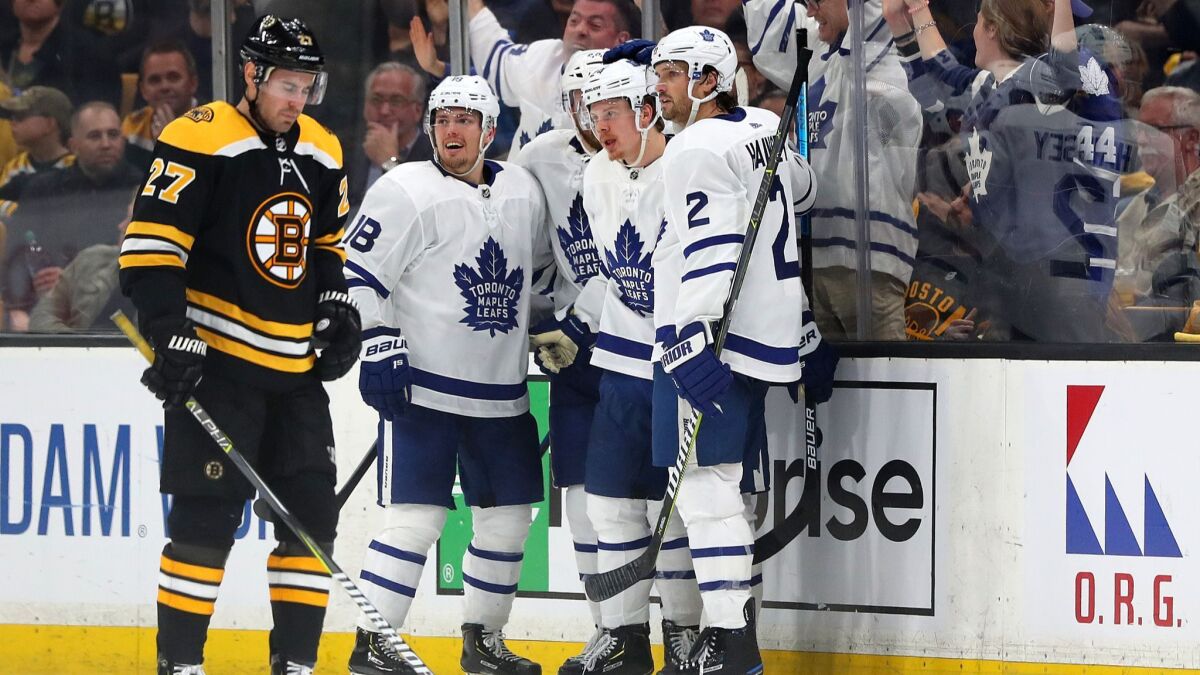 Andreas Johnsson (18) of the Toronto Maple Leafs and Ron Hainsey (2) celebrate with Kasperi Kapanen (24) after he scored a goal as John Moore (27) of the Boston Bruins looks on during the third period.