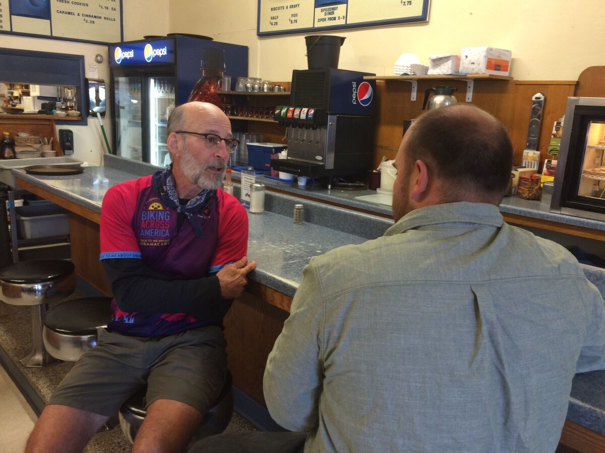 Dr. Paul Gordon talks with a 28-year-old railroad worker at the Speedway Diner in Forsyth, Mont., during his summer-long bike trip devoted to talking to Americans about Obamacare.