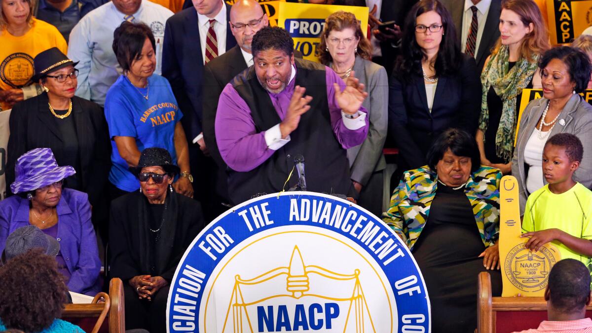 North Carolina NAACP president Rev. William Barber is surrounded by supporters in Richmond, Va. on June 21 during a news conference held to discuss North Carolina's voting laws.