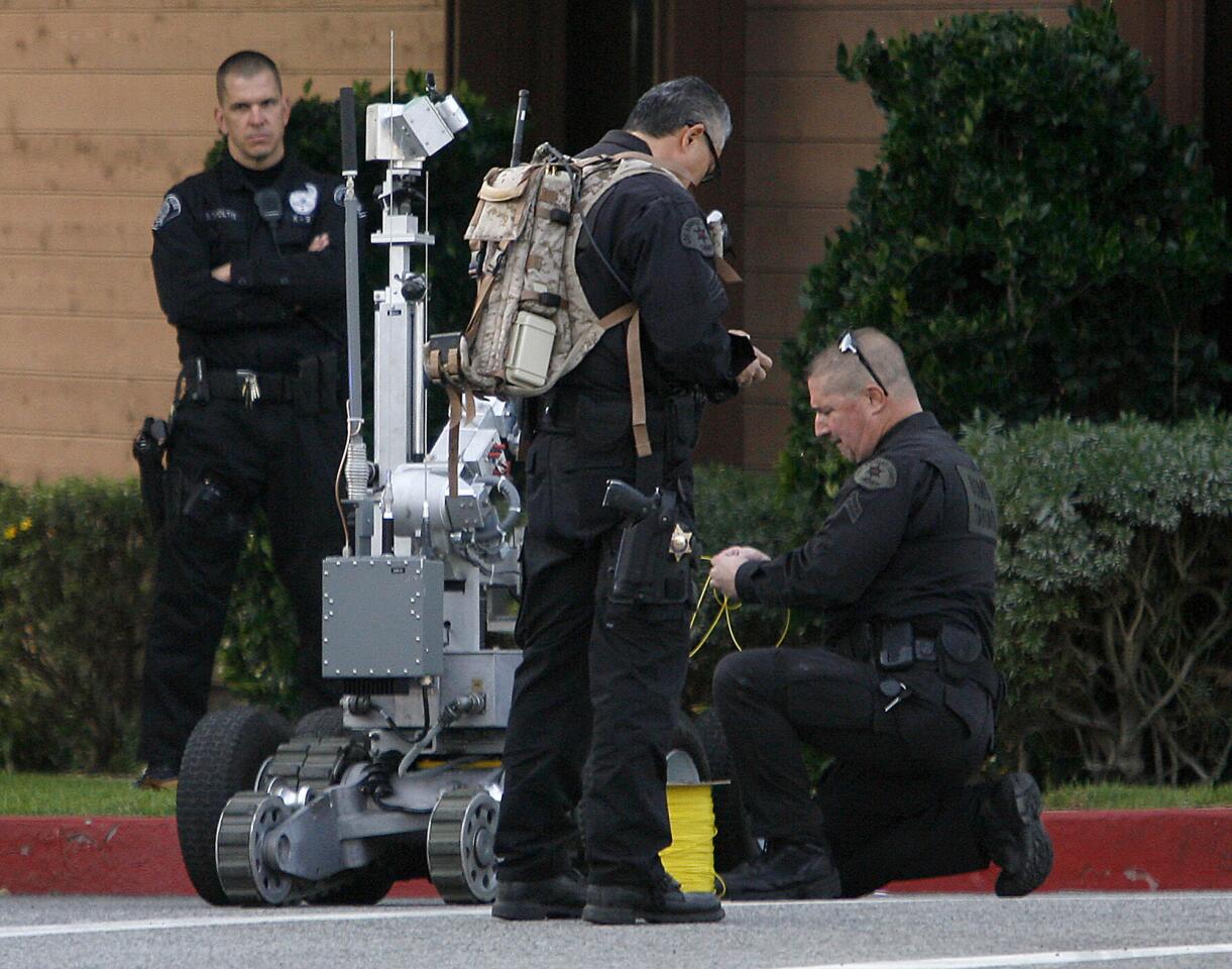 A Glendale police officer stands by at left as L.A. County Sheriff Bomb Squad officers prepare a remote controlled rover that would detonate a suspicious package found at the Temple Sinai of Glendale on the 1200 block of N. Pacific Ave. in Glendale on Friday, December 21, 2012.