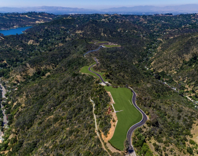 Aerial view of the development with a road and grass surrounded by shrubbery.