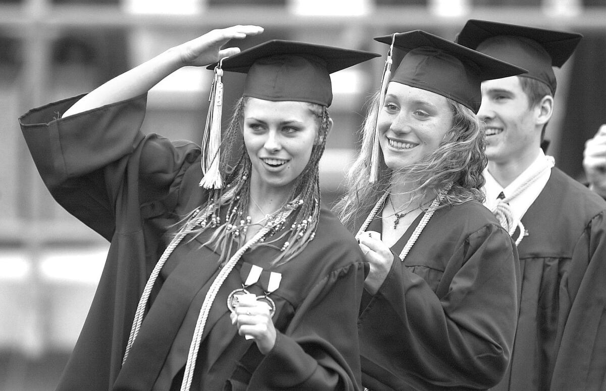 Photographed in 2003, from left, Estancia High School graduates Krystal Farthing and Karleen Curran get ready to receive their diplomas.