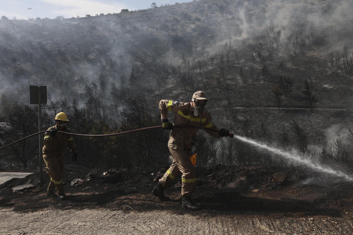 Firefighters operate during a wildfire in Voula suburb, in southern Athens, Greece, Saturday, June 4, 2022. A combination of hot, dry weather and strong winds makes Greece vulnerable to wildfire outbreaks every summer. (AP Photo/Yorgos Karahalis)
