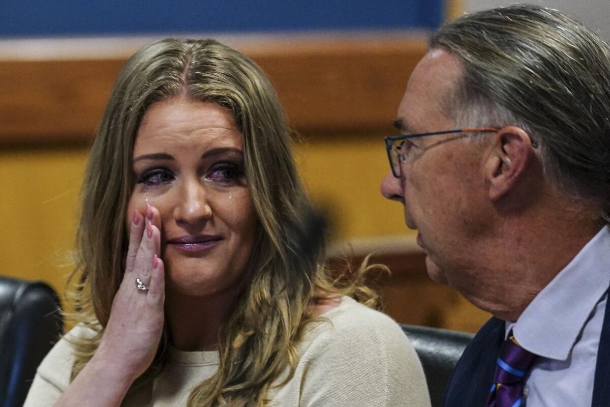 Former Trump attorney Jenna Lewis holds a hand to her face as she speaks to her lawyer