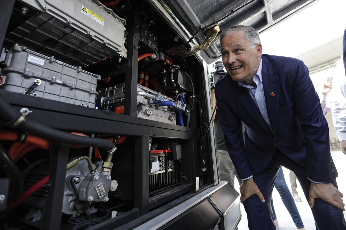 Washington Gov. Jay Inslee, who is seeking the Democratic nomination for president, looks at components of an electric bus at the Los Angeles Department of Transportation bus depot.