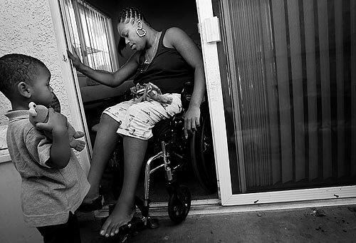 Tyrin Tisdale Jr., 2, watches his mother, Rose Smith, as she struggles to get into their apartment, which has been adapted for her needs. She was paralyzed from the waist down a year ago, struck by a stray bullet outside her home in Nickerson Gardens. She was 23, the mother of two and nearly four months pregnant. Her life since then has been filled with pain, struggle and a dream of a better life for her children.