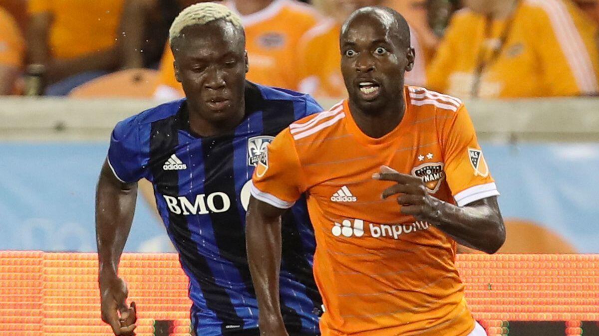 Houston Dynamo defender DaMarcus Beasley (7) looks up for a pass while Montreal Impact forward Ballou Jean-Yves Tabla (13) gives chase during the second half of an MLS soccer match onJuly 5 in Houston.