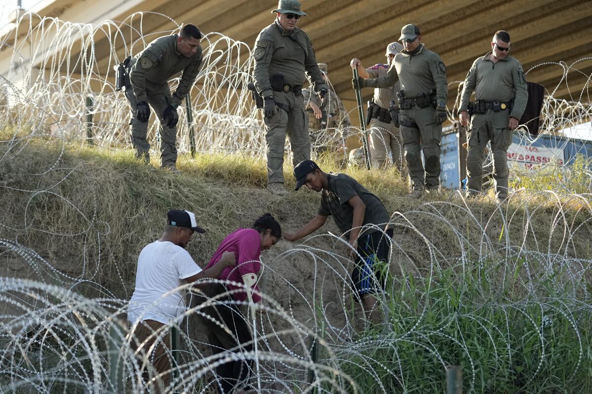 Soldados y guardias de Texas ayudan a una migrante que quedó atrapada en un alambre de púas 