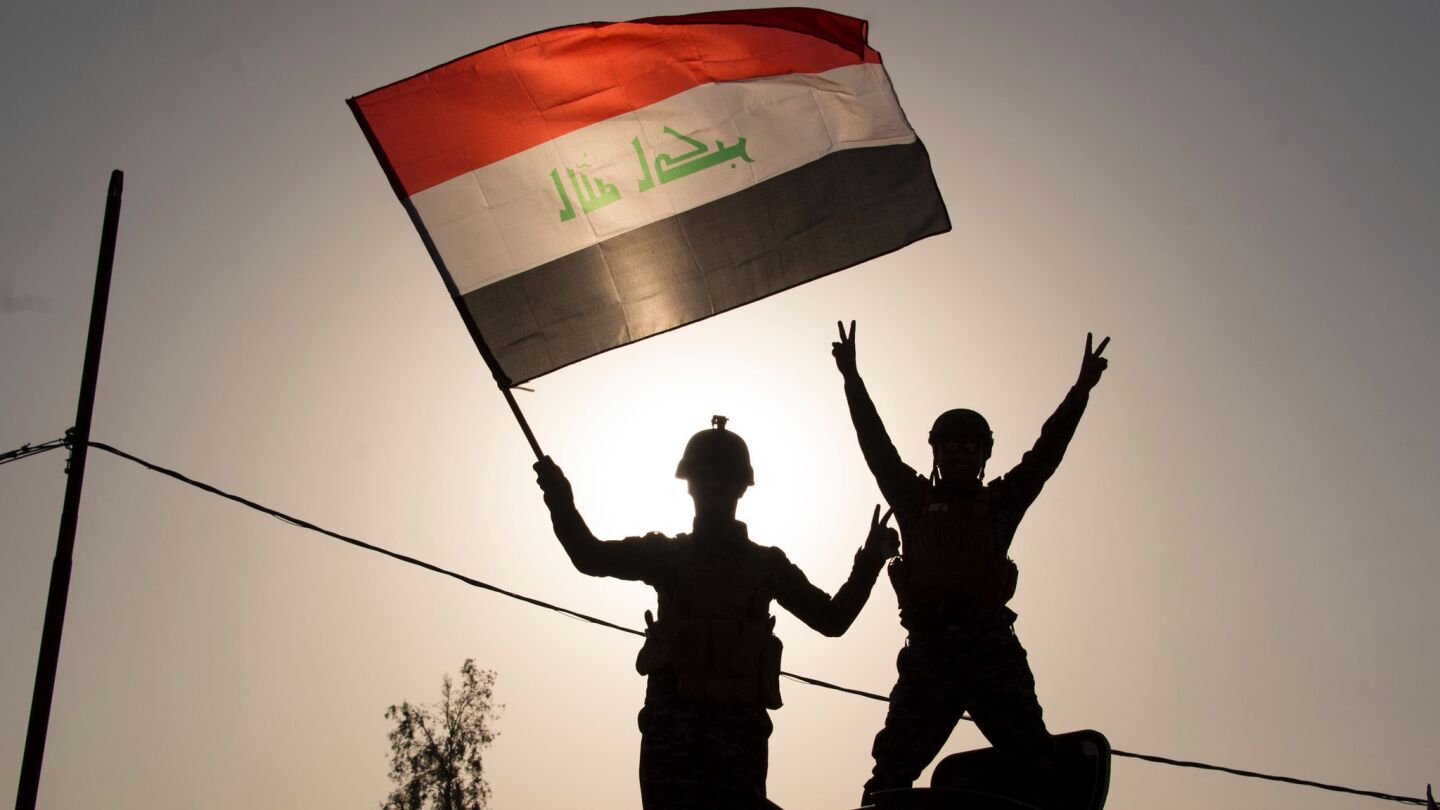 Iraqi federal police officers wave the national flag as they celebrate in the Old City of Mosul.